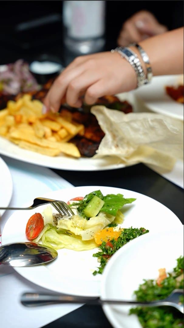 A guest reaching for a plated dish at Cattleya